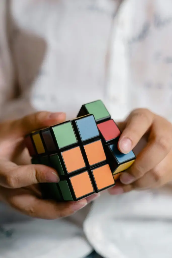 Close-up of hands manipulating a colorful Rubik's Cube, focused on puzzle-solving skill.